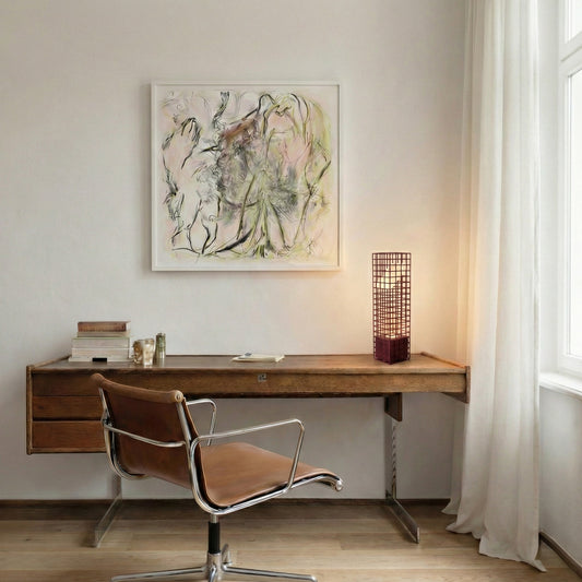 Modern home office with wooden desk, leather chair, and abstract art on the wall. A maroon mesh lamp is lighted up on the desk.