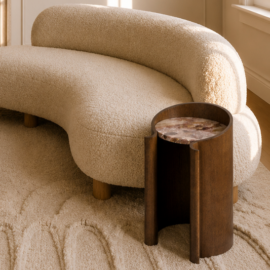 curved wood veneer side table in walnut with a marble top by an off white sofa