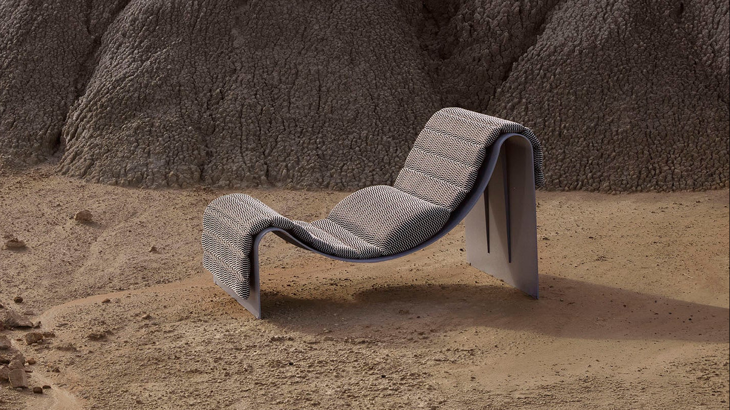 Modern lounge chair in a desert landscape with rocky formations.
